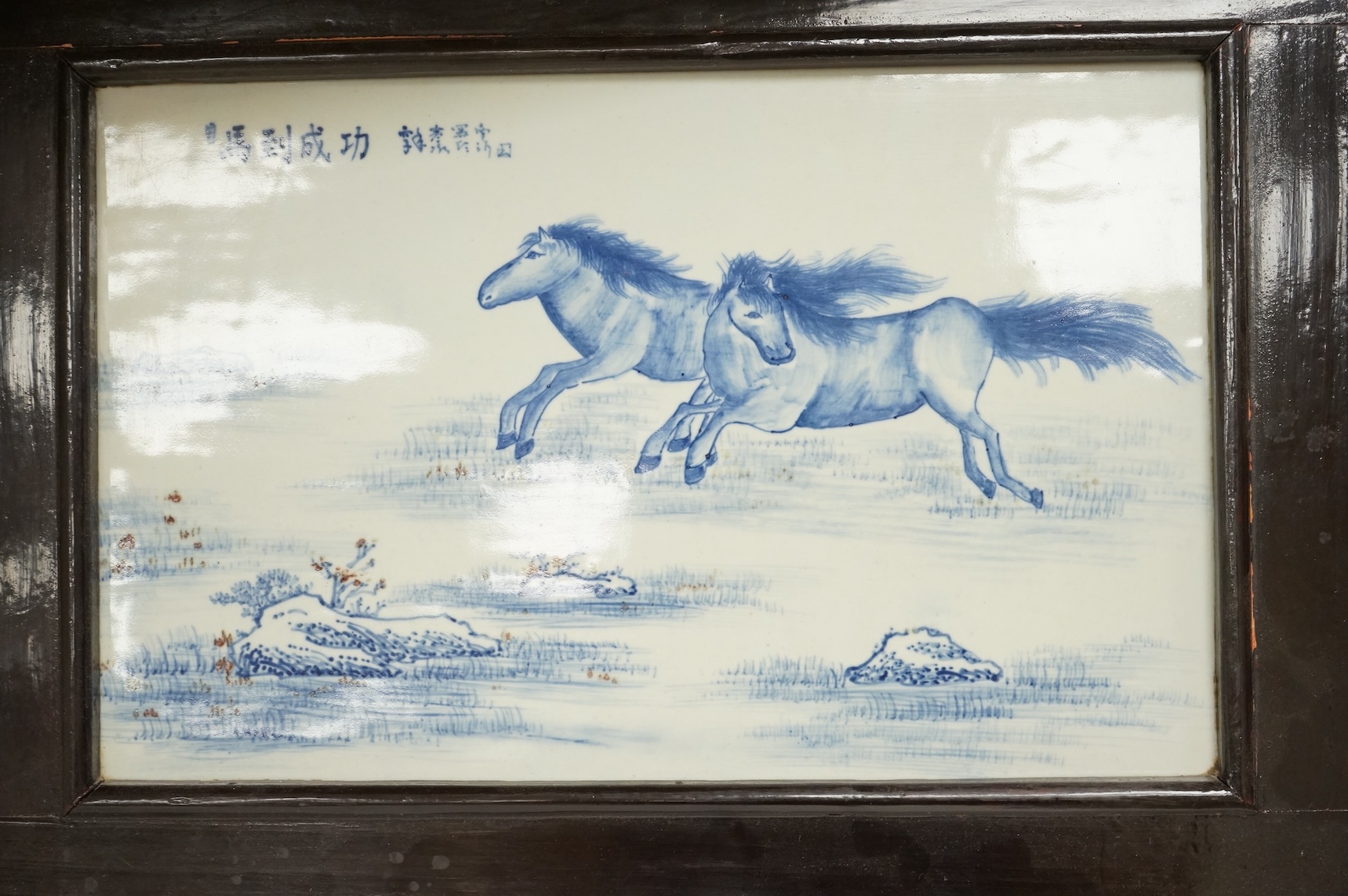 A Chinese framed blue and white porcelain panel depicting two horses, framed, overall 35 x 48cm